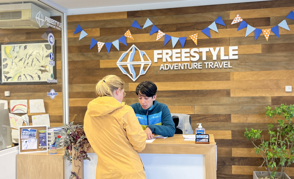 Freestyle office located in Ushuaia, guest services Yesica in front desk helping a passenger